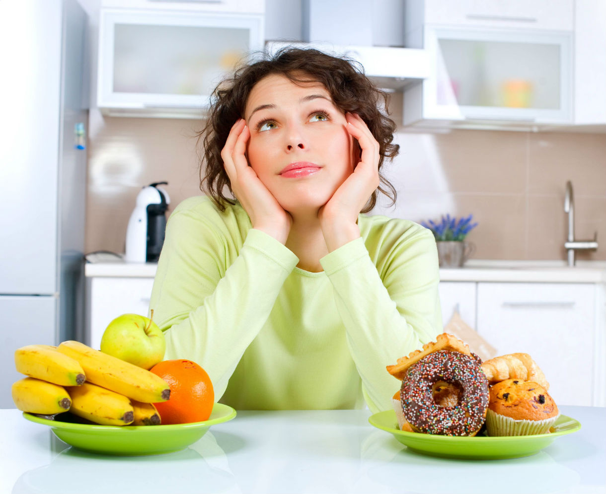 healthy - woman deciding btwn donuts and fruit