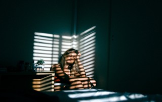 girl in dark with shadows from blinds