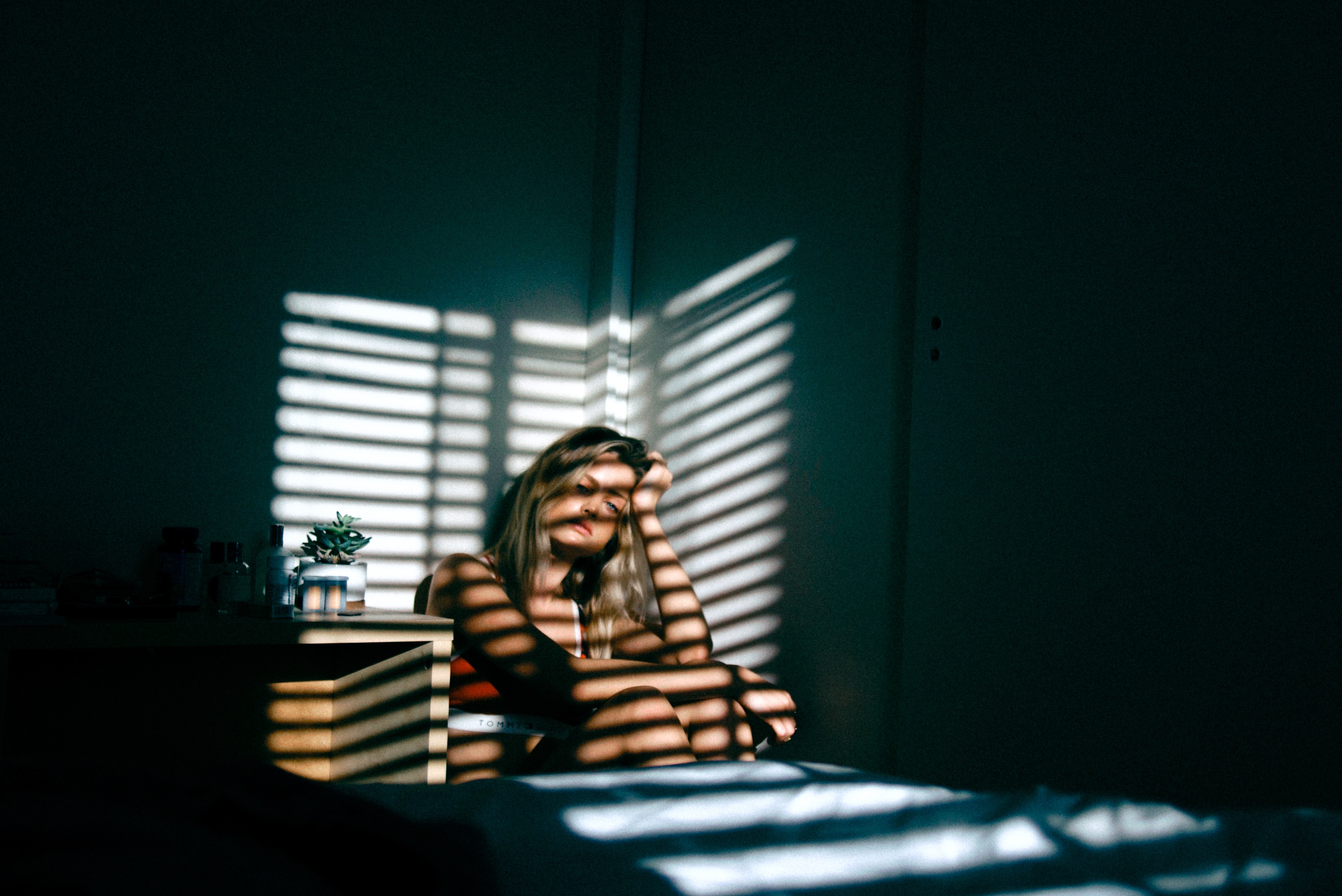 girl in dark with shadows from blinds