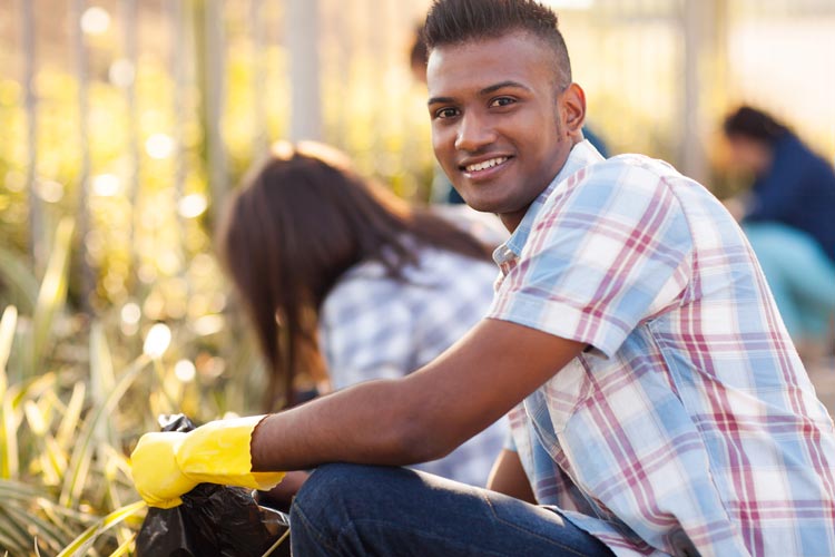 young man picking up litter with group