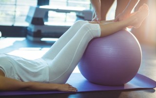 woman exercising with yoga ball and trainer