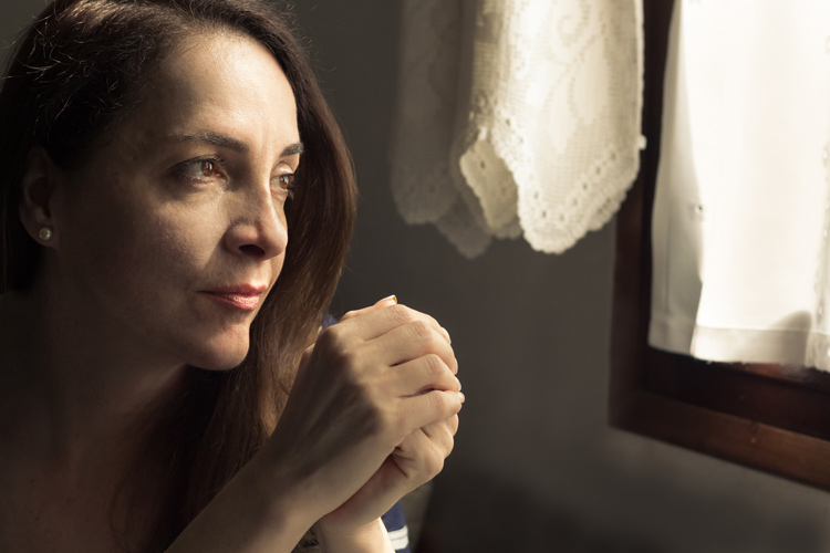 thoughtful woman looking out window of home - victim mentality