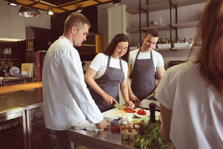 happy couple in kitchen with chef taking cooking class - sober date