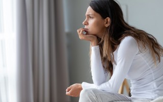 young woman sitting on the edge of her bed thinking - fear