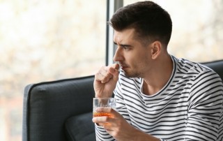 young man holding alcoholic drink about to cough - immune system