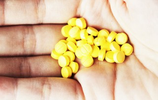 close up of a hand full of small yellow pills - Clonazepam Addiction