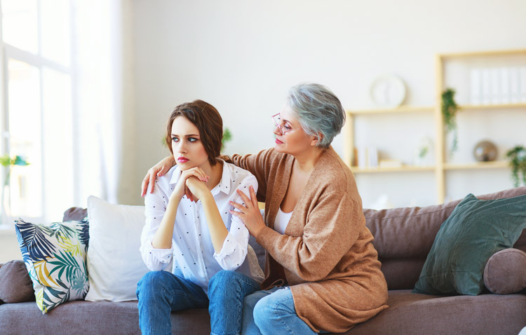young adult woman sitting on couch with her mom - adult child