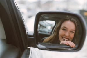 view of woman in side mirror of car smiling - guilt and shame