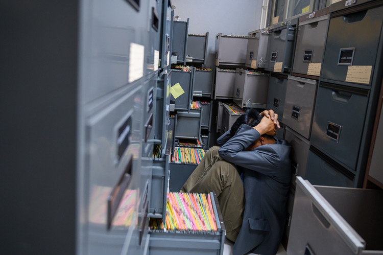 man sitting on the floor of a file room full of filing cabinets - low frustration tolerance