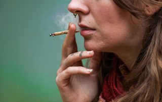closely cropped shot of a young woman smoking a small marijuana cigarette - marijuana use