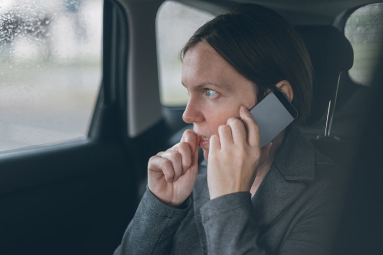 woman on cell phone in car with her hand to her mouth, looking extremely anxious or even scared - anxiety disorders
