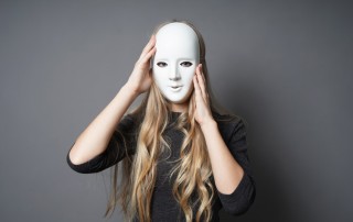 woman with long blonde hair holding a plain white mask up to her face - addictive personality