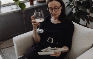 Older woman looking at photos while drinking wine