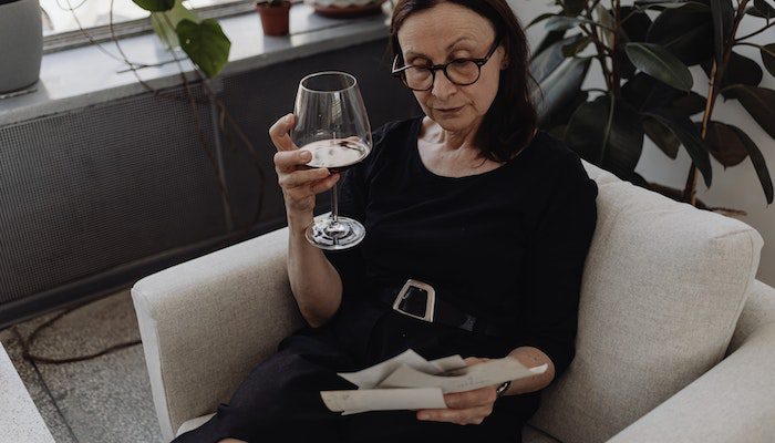 Older woman looking at photos while drinking wine