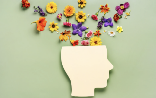 A profile of a wooden head with flowers on top.