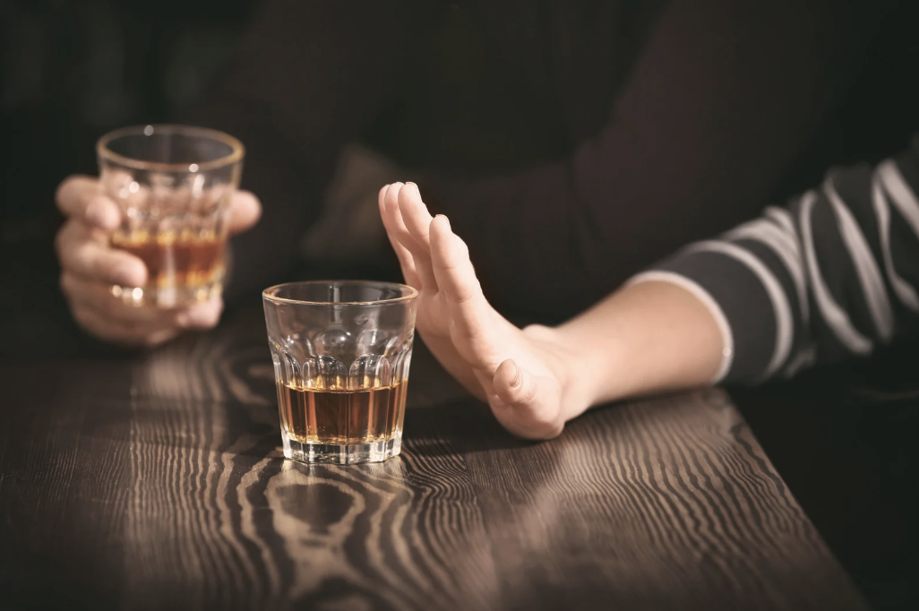 A person's hand pushing away alcohol.